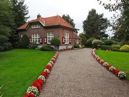 walk path decorated with flowers to old red brick building in park, netherlands