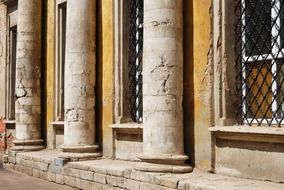 grunge facade with columng and grates on windows