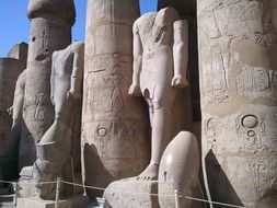 carved columns and giant stone figures, ruin of ancient temple, egypt, luxor