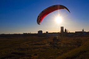 person on paraglider at sunset city skyline