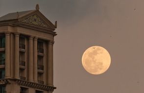 scenic full moon in sky at facade of old building