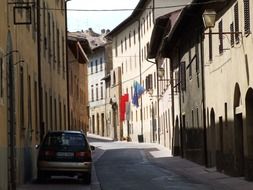 flags on facade of old building on alley, italy, san gimagnano