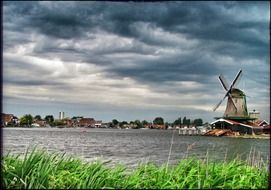 windmill in countryside under stormy clouds, netherlands, zaanse schans