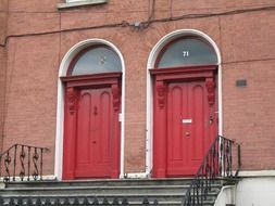 two old arched red doors on porch, ireland, dublin