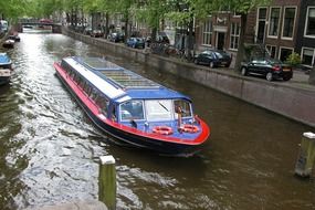 tourist boat on canal in city, netherlands, amsterdam