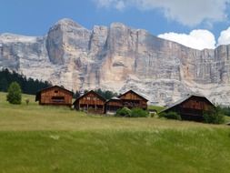 scenic landscape, wooden buildings on meadow at dolomites, italy