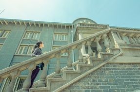 young asian girl stands on stairs at facade of old building, china, nanjing