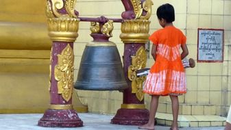 asian child girl with stick at bell, myanmar