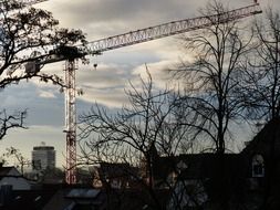 boom of tower crane at evening sky above town