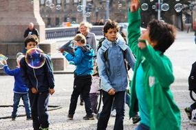 children playing soap bubbles in city on the square, denmark, copenhagen