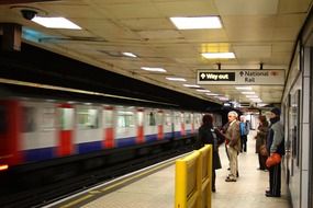 people on platform at train in subway station, uk, england, london