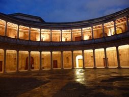 illuminated colonnada of old palace at night, spain, granada