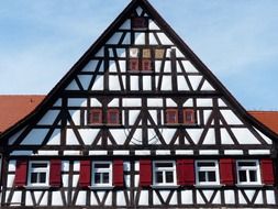 traditional truss building with red shutters on windows