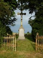 aged stone cross behind fence in countryside, france