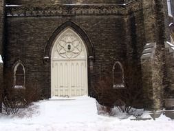 aged door of church on porch at snowy winter