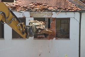 excavator demoliting old house