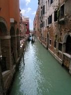 man in goldola on channel in old alley, italy, venice