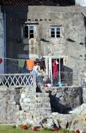 woman hanging clothing on line on terrace of old house, spain, galicia, a guarda