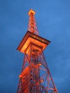 orange illuminated radio tower at deep blue sky, germany, berlin