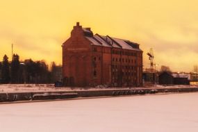 old brick building on waterfront at winter sunset, finland