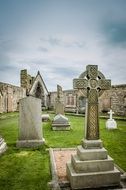 aged stone monuments on cemetery under cloudy sky, uk, scotland