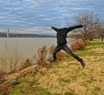 headless man jumping on riverside at fall