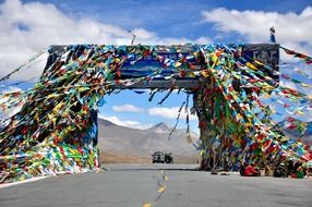colorful flags on gates above highway in scenic mountain landscape, china