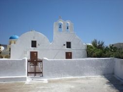 White orthodox church behind white stone fence, greece, santorini