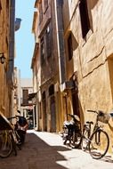 bikes and bicycles at walls in old alley, greece