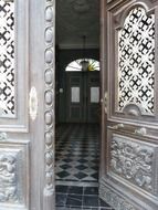 partially opened wooden entrance doors with traditional carving and patterned glass, portugal