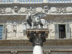 Beautiful winged lion at pillar statue near the patterned building, italy, verona