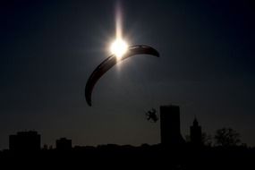 paraglider wing at sun above city