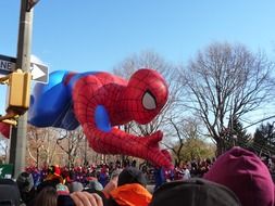 floating spiderman figure above crowd of people in park, usa, manhattan, new york city
