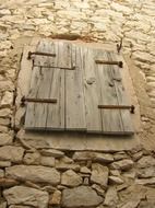 window closed with weathered wooden shutters on wild stone wall, croatia, susak island house