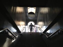 man walks down long dark stairway