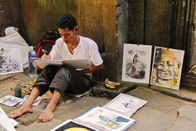 young artist painting at ancient angkor wat temple, cambodia, siem reap