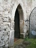 open metal grid door in aged stone wall