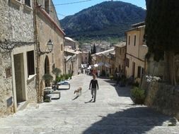 man with dog walking up scenic street, spain, majorca