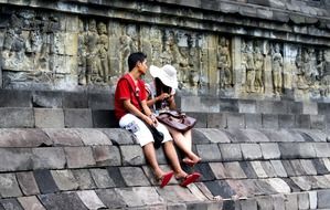 young asian boy and girl sitting at ancient buddhist temple, indonesia, java