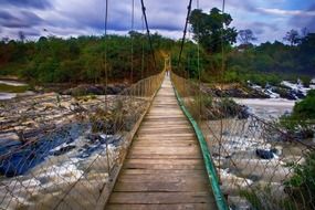 long pedestrian suspension bridge across foamy waterflow