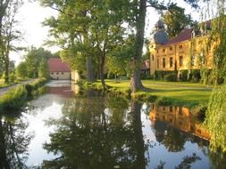 old buildings mirroring on water in park at summer, germany