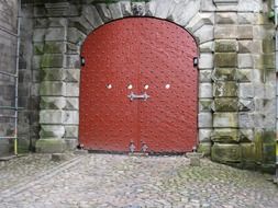 red metal sheet gate in aged grey stone wall, denmark