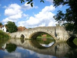 medieval arched stone bridge in countryside at summer