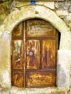 closed rusty metal door in the old stone wall