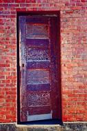 partly open old wooden door in brick wall