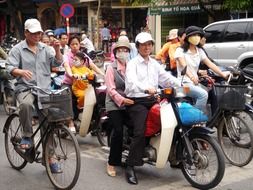 people riding motorcycles and bicycles on street in city, vietnam, hanoi