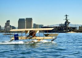 seaplane taking off water in view of naval ship at city, usa, california, san diego