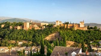 alhambra fortress on green mountain above old city, spain, granada