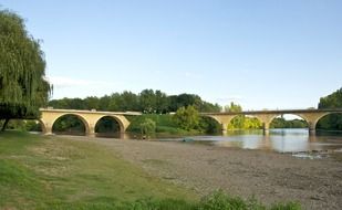 old stone bridge across calm river at summer, france, dordogne