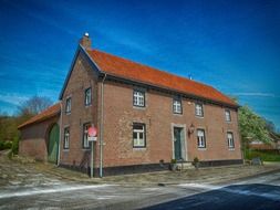 old two-storey red brick building at road, netherlands, limburg